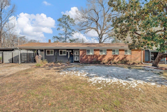 single story home featuring an attached carport, a chimney, and brick siding