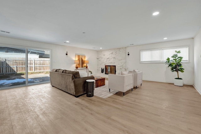 living area featuring light wood-style flooring, a fireplace, visible vents, and recessed lighting