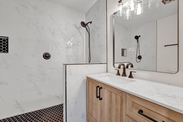 full bathroom featuring tiled shower and vanity