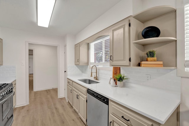 kitchen featuring open shelves, light countertops, light wood-style flooring, appliances with stainless steel finishes, and a sink