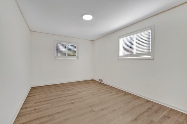 spare room with light wood finished floors, visible vents, and baseboards