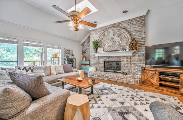 living room featuring a textured ceiling, wood finished floors, vaulted ceiling, a brick fireplace, and crown molding