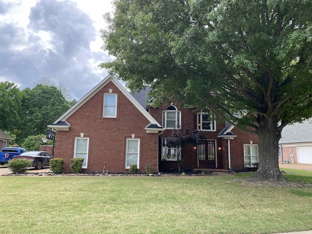 traditional-style house featuring a front lawn, french doors, and brick siding