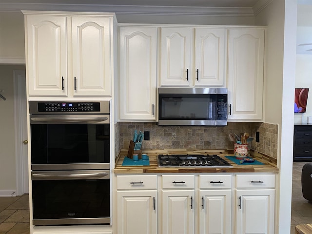 kitchen featuring stainless steel appliances, ornamental molding, backsplash, and white cabinetry