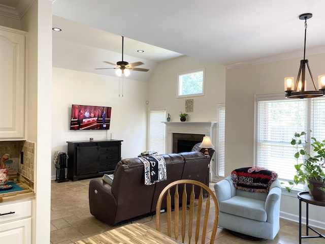 living room featuring crown molding, a fireplace, vaulted ceiling, baseboards, and ceiling fan with notable chandelier