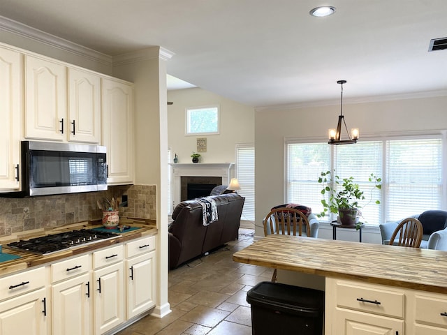 kitchen featuring butcher block counters, a fireplace, appliances with stainless steel finishes, and stone tile floors