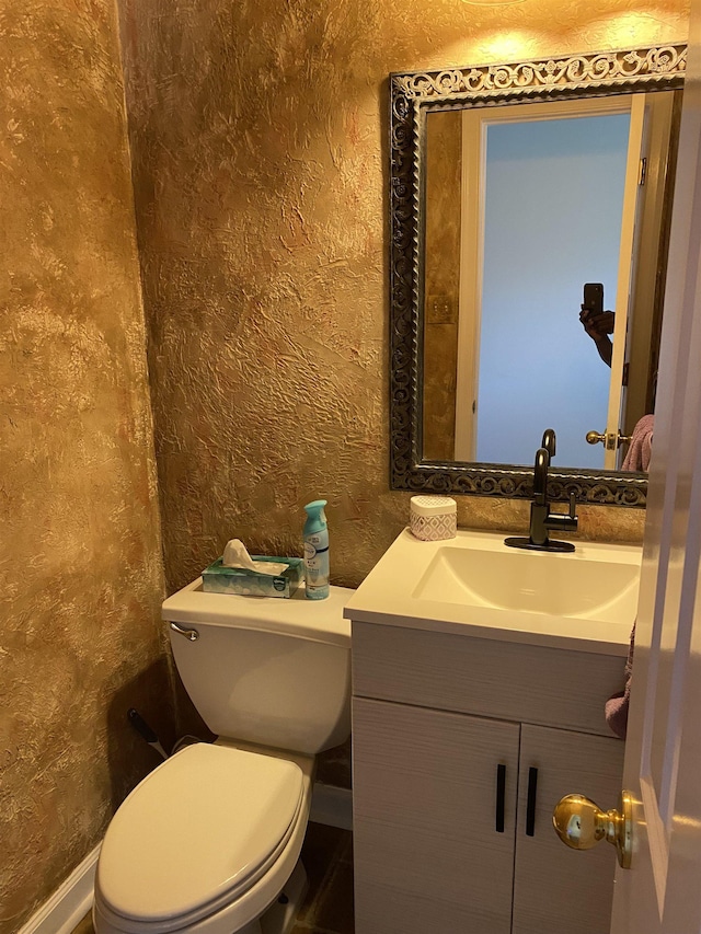 bathroom with a textured wall, vanity, and toilet