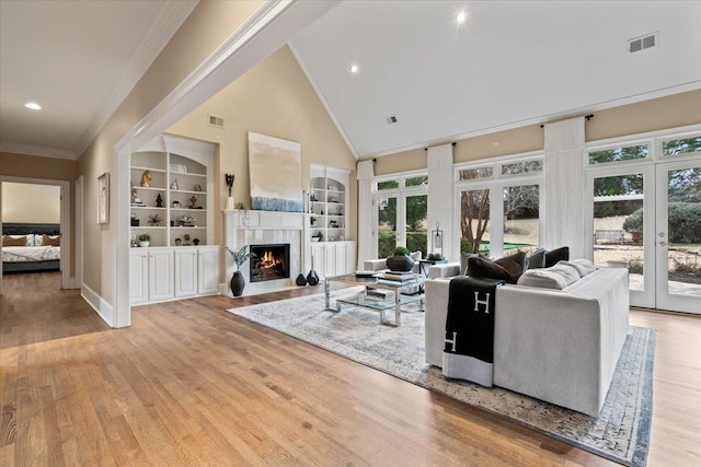 living room with a premium fireplace, visible vents, built in features, and french doors