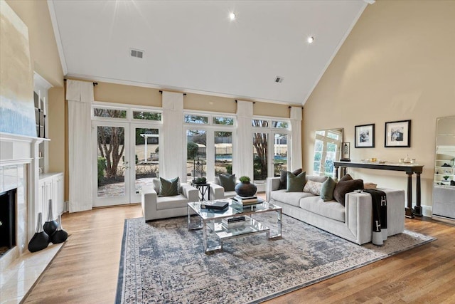 living area featuring high vaulted ceiling, a fireplace, visible vents, and ornamental molding