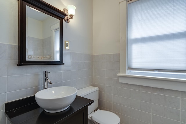 half bathroom featuring toilet, tile walls, and vanity