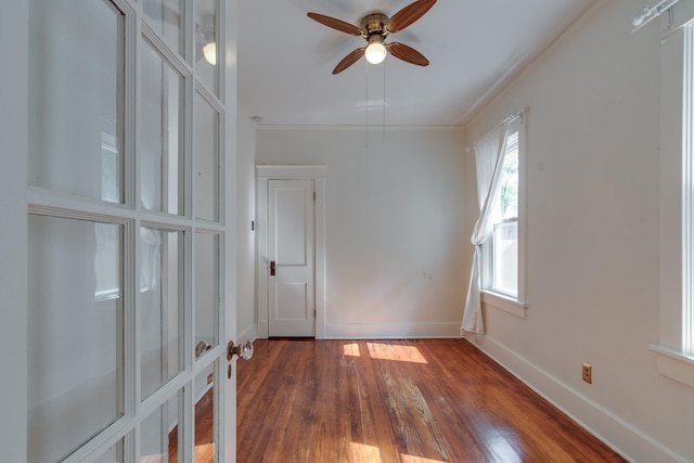 unfurnished room with dark wood-style flooring, crown molding, baseboards, and ceiling fan