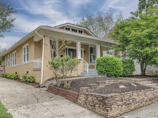 bungalow with a porch and brick siding