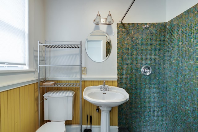 bathroom featuring toilet, a wainscoted wall, and a tile shower