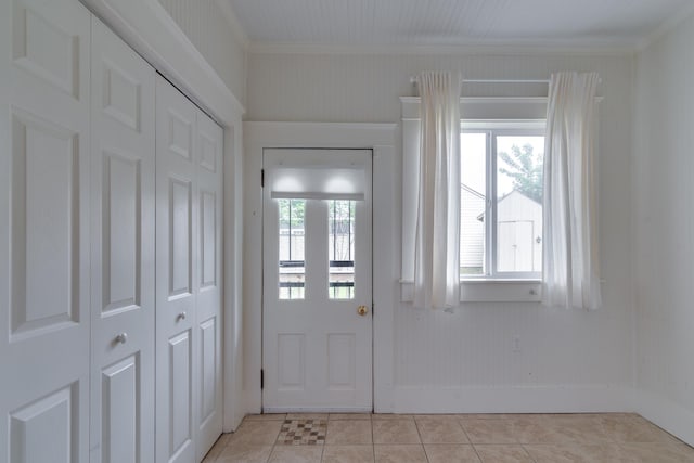 interior space featuring baseboards, light tile patterned flooring, and crown molding