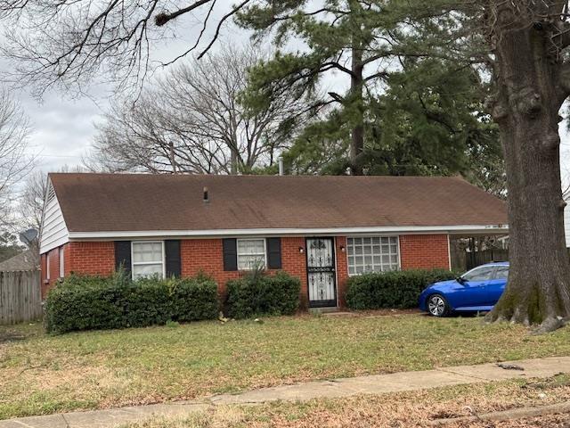 ranch-style house featuring a carport, brick siding, a front yard, and fence