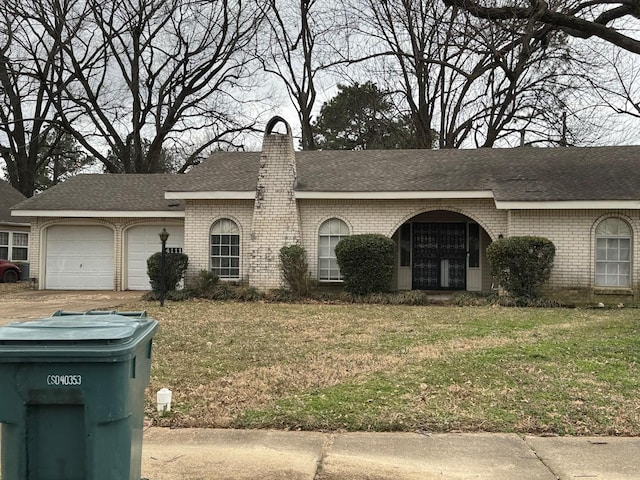 single story home featuring a garage, a front yard, brick siding, and a chimney