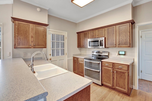 kitchen featuring brown cabinets, crown molding, appliances with stainless steel finishes, a sink, and light wood-type flooring