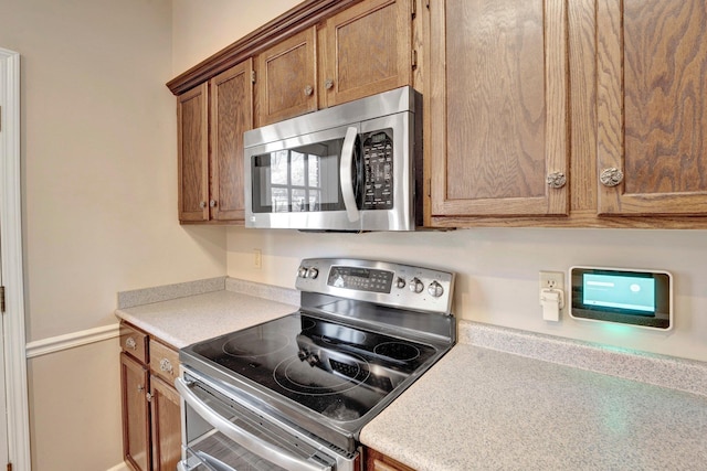 kitchen featuring appliances with stainless steel finishes, brown cabinetry, and light countertops