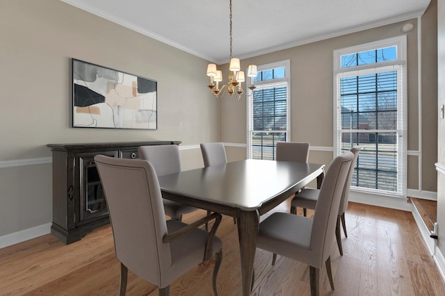 dining room featuring baseboards, ornamental molding, light wood-type flooring, and an inviting chandelier