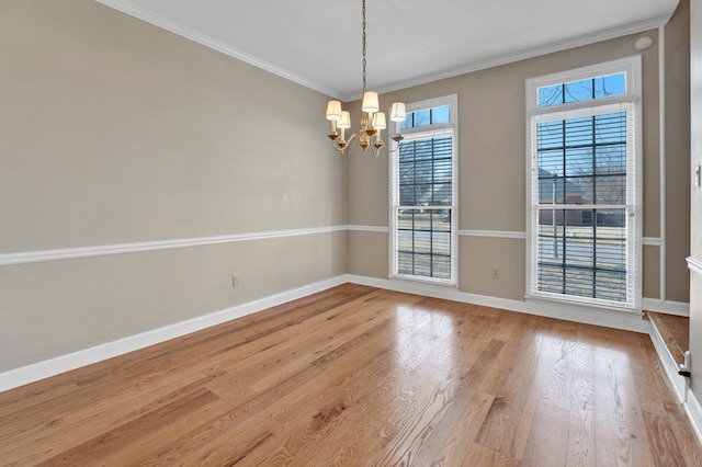 unfurnished room with ornamental molding, light wood-type flooring, a chandelier, and baseboards