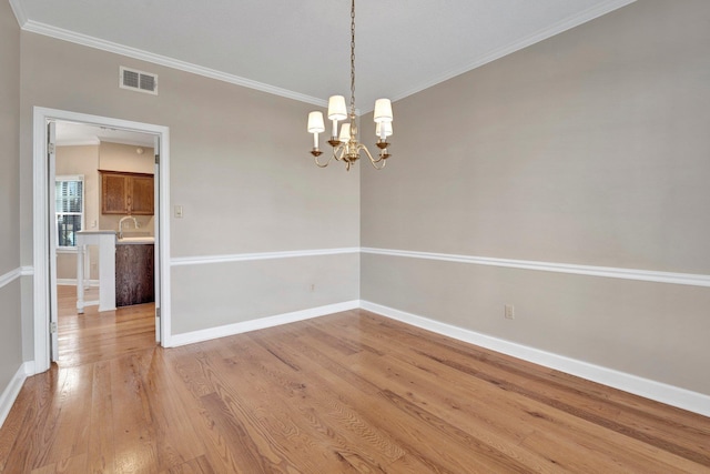 spare room featuring ornamental molding, light wood-type flooring, visible vents, and baseboards