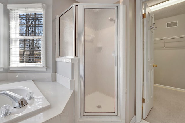 bathroom featuring a stall shower, a healthy amount of sunlight, visible vents, and a walk in closet