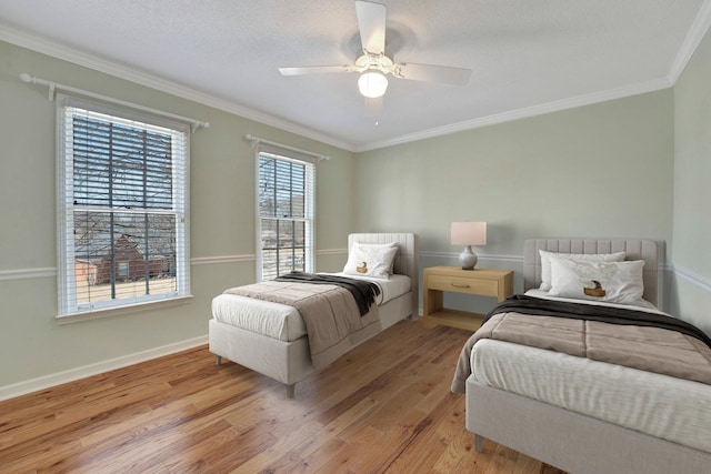 bedroom with light wood-style floors, ornamental molding, baseboards, and ceiling fan