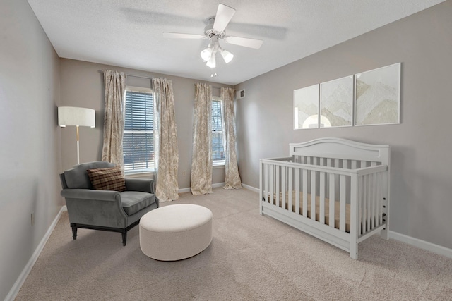 bedroom featuring a textured ceiling, visible vents, baseboards, a nursery area, and carpet