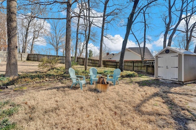 view of yard featuring a storage shed, a fenced backyard, a fire pit, and an outdoor structure