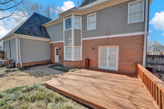 rear view of property with a deck, central air condition unit, brick siding, fence, and french doors