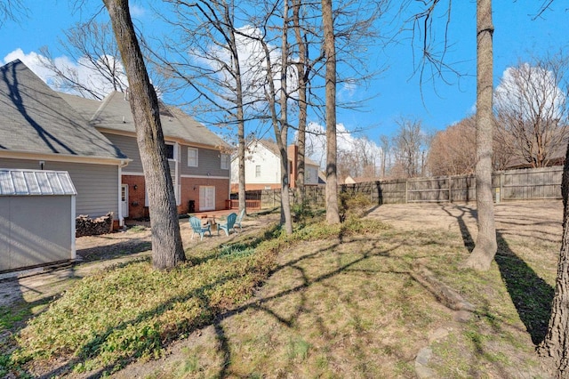 view of yard featuring a storage shed, an outdoor structure, and a fenced backyard