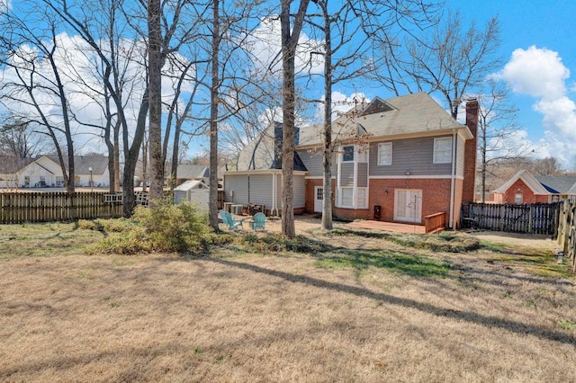 back of house featuring brick siding, a chimney, a lawn, fence private yard, and an outdoor structure