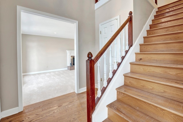 stairway with a fireplace, baseboards, wood finished floors, and carpet flooring