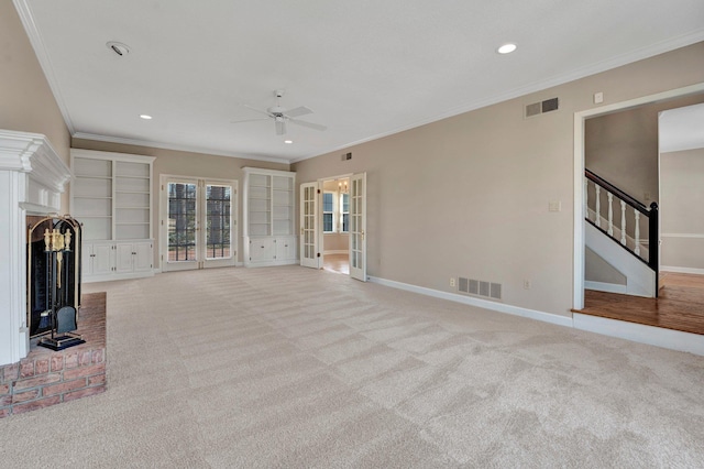 unfurnished living room with a brick fireplace, stairs, visible vents, and light colored carpet