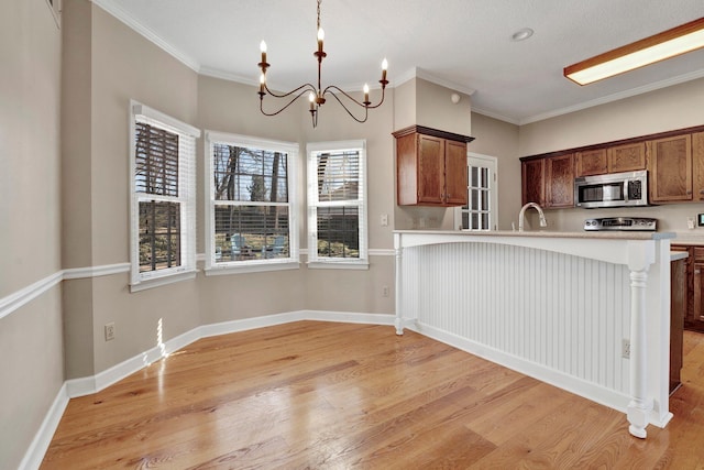 kitchen featuring a sink, light countertops, light wood-type flooring, stainless steel microwave, and crown molding