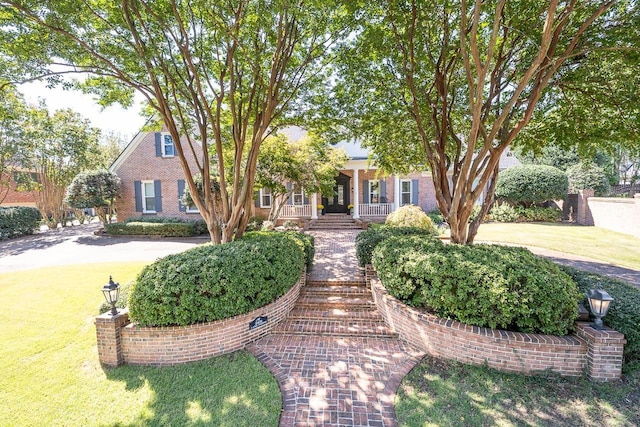 view of front of house with a porch, a front yard, and brick siding