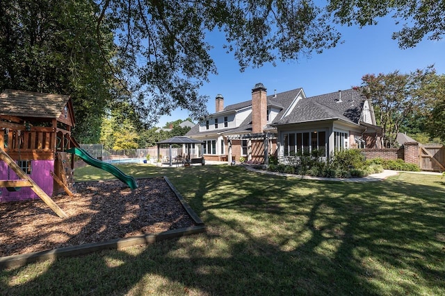 back of house with a gazebo, a lawn, a playground, and fence private yard