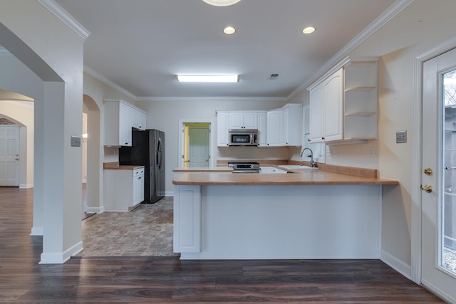 kitchen featuring arched walkways, appliances with stainless steel finishes, ornamental molding, white cabinets, and a peninsula