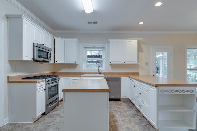 kitchen featuring a peninsula, stainless steel appliances, white cabinetry, visible vents, and open shelves