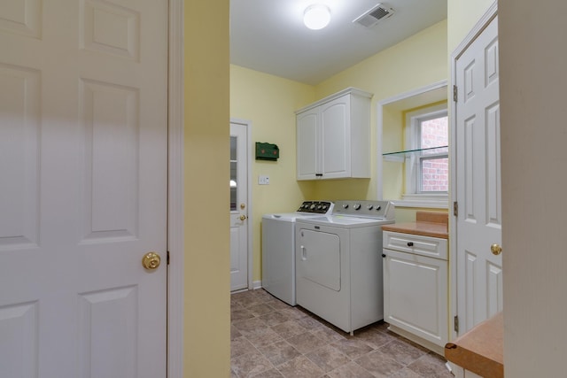 clothes washing area featuring cabinet space, washing machine and dryer, and visible vents