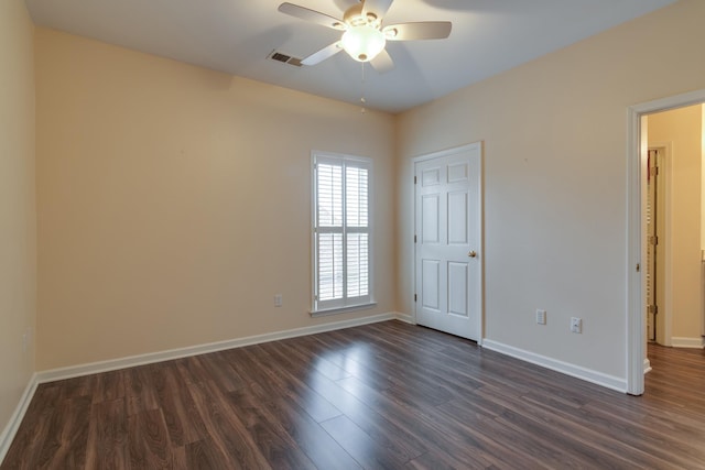 spare room with a ceiling fan, dark wood finished floors, visible vents, and baseboards