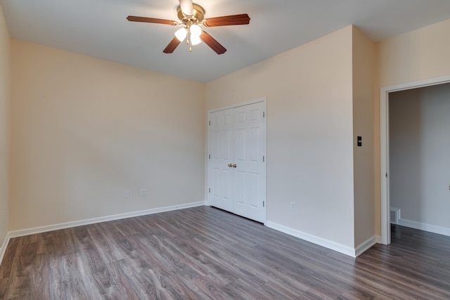 unfurnished bedroom with dark wood-style flooring, a closet, visible vents, and baseboards