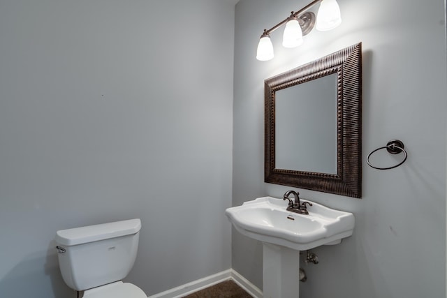 half bath featuring baseboards, a sink, and toilet