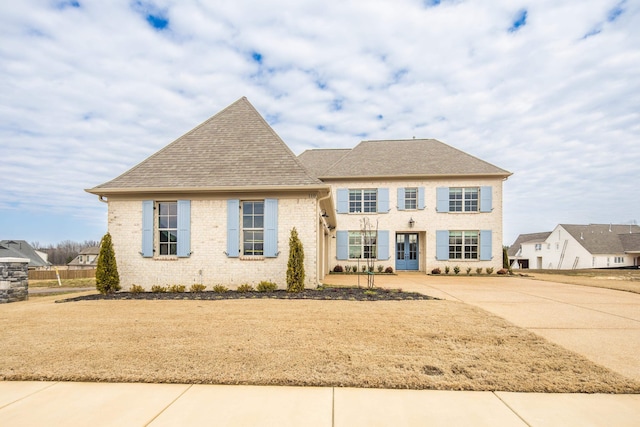 view of front of house featuring french doors, a shingled roof, and brick siding