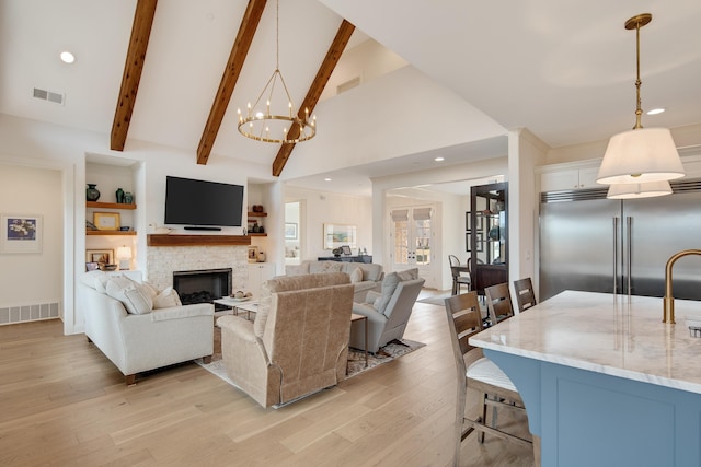 living area featuring light wood-type flooring, beam ceiling, visible vents, and a stone fireplace