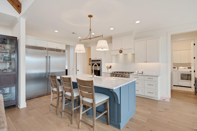 kitchen featuring light wood-style floors, white cabinetry, appliances with stainless steel finishes, and washer and clothes dryer