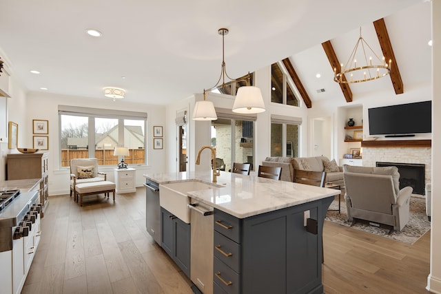 kitchen with light stone counters, gray cabinetry, light wood-style floors, a sink, and beamed ceiling