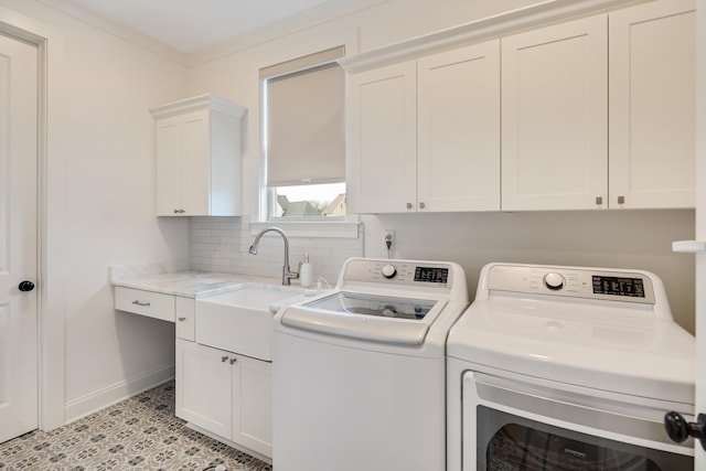 washroom featuring cabinet space, a sink, baseboards, and separate washer and dryer