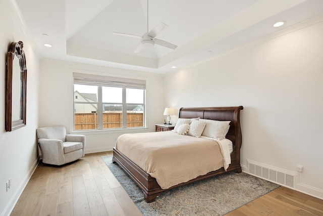 bedroom with light wood finished floors, recessed lighting, a raised ceiling, visible vents, and baseboards