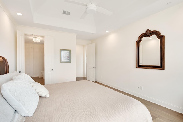 bedroom featuring recessed lighting, wood finished floors, visible vents, baseboards, and a tray ceiling